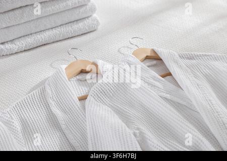 Clean bathrobes and towels on bed indoors, closeup Stock Photo