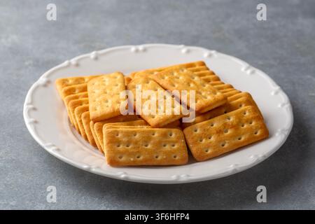 Salted Biscuit Crackers Served on a White Plate Over Gray Background Stock Photo