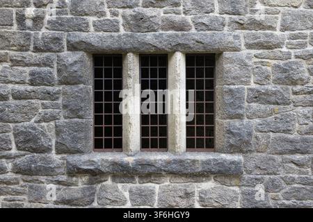Stone mullioned window with iron security grille set into rustic ashlar wall at Rivington Terraced Gardens, Lancashire, UK. Stock Photo