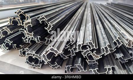 Close-up of stacked black aluminium extrusion profiles on a commercial construction site, used for curtain wall, window, door and façade systems in mo Stock Photo