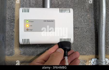 Technician testing a carbon monoxide detector using calibration gas during routine maintenance of a commercial gas detection system. Industrial safety Stock Photo