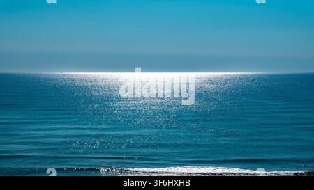 Sunlight reflecting on calm blue sea beneath a clear horizon Stock Photo