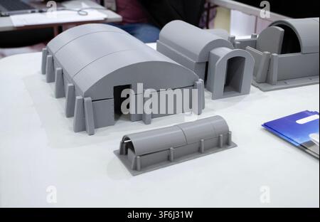 Prototype scale models of ground modular shelters printed on 3D printer from molten plastic. Ground-based defensive structures with arched roof and fortified entrances created 3D printer. 3D printing Stock Photo