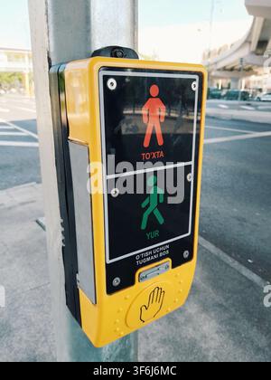 Tashkent, Uzbekistan - April 10, 2026 - Yellow push button box with red and green pedestrian icons for safe street crossing at traffic lights. Stock Photo