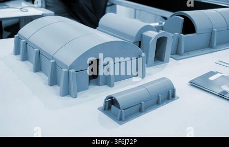 Prototype scale models of ground modular shelters printed on 3D printer from molten plastic. Ground-based defensive structures with arched roof and fortified entrances created 3D printer. 3D printing Stock Photo