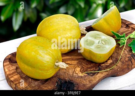 Fresh lemon cucumber Cucumis sativus whole and sliced on rustic wooden board Stock Photo