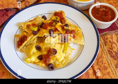 Mexican Cheese nachos with cheese sauce, salsa and black olives. Stock Photo