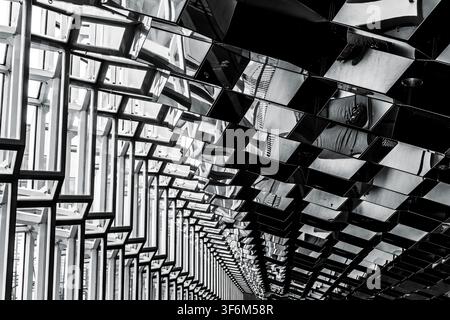 Modern glass building interior featuring geometric panels and reflective surfaces Stock Photo
