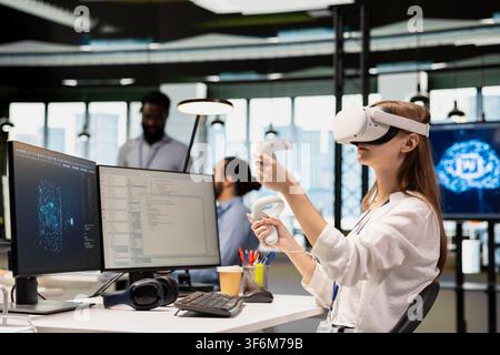 Junior programmer using virtual reality at work, testing generative AI machine learning algorithms. Young worker wearing VR goggles equipment scaling productivity with AI large language model code Stock Photo