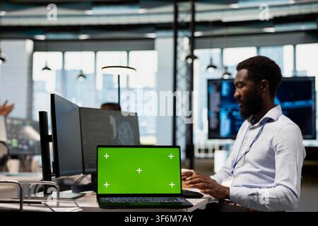 Engineer using isolated screen laptop, writing code, developing machine learning APIs. IT expert in office troubleshooting software errors using artificial intelligence tech on chroma key notebook Stock Photo