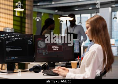Female software developer in tech startup office struggling to fix app errors while coding. Young employee dealing with computer glitches while coding in software development company Stock Photo