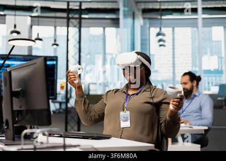 Computer scientist wearing VR headset at office desk developing programs using AI automation. Tech company employee using virtual reality, debugging applications with artificial intelligence Stock Photo