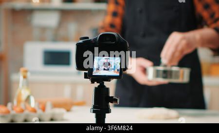 The hand movement is shown in close view as the male baker records a baking demonstration for online viewers at home during online cooking instruction. Stock Photo