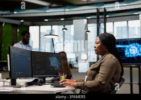 System administrator in office using AI on computer to streamline app development. IT professional at desk using PC to run debugging programs with machine learning technology Stock Photo