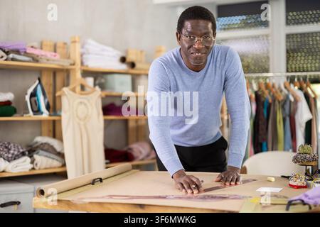 African American man tailor draw dress pattern on paper. Craftsman ...