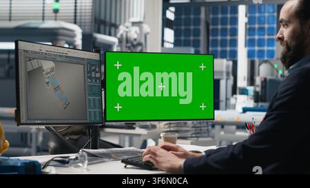 Male technician in a solar panel plant uses chroma key for system performance, playing a crucial role in monitoring efficiency and workplace safety. Renewable power concept. Camera B. Stock Photo