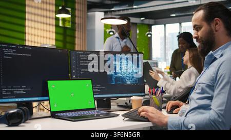 Admin in office using isolated screen laptop, automating repetitive tasks with AI scripts. IT expert using artificial intelligence on chroma key device to speed up feature implementation, camera A Stock Photo