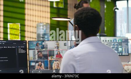 Tech startup office team collaborating via videocall, doing brainstorming on backup solutions to protect against data loss. Remote developers doing AI coding during online teleconference, camera A Stock Photo