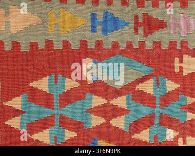 Kilim rug displaying a detailed, handwoven textile background featuring colorful geometric patterns, abstract shapes, and traditional cultural symbols Stock Photo