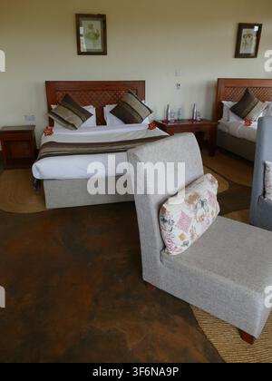 Relaxing hotel room with two double beds, armchairs, wooden furniture and a polished concrete floor Stock Photo