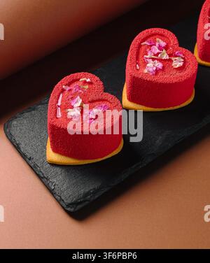 Red heart-shaped cakes with mousse and rose petals presenting a sweet romantic dessert Stock Photo