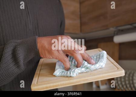 Hand holding a towel on a wooden cutting board Stock Photo