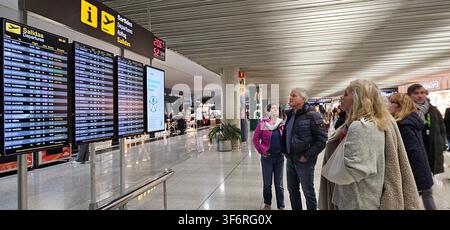 Departures information boards draw waiting passengers checking flight listings beneath multilingual departure signage in the concourse. Palma de Mallo Stock Photo