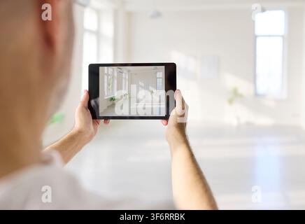 Designer using tablet to photograph bright modern interior room in spacious hall Stock Photo