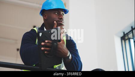 Architect, thinking and black man with tablet in building for construction safety or security. Thoughtful, male person or civil engineer with Stock Photo