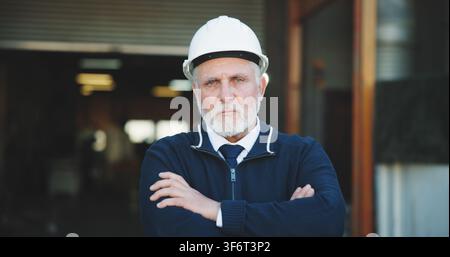 Architect, portrait and man with arms crossed on construction site, serious or property development. Confident, civil engineer and mature person with Stock Photo