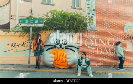 Friends gathering near a seal statue on a street corner, Longjiang Road, Qingdao, China Stock Photo