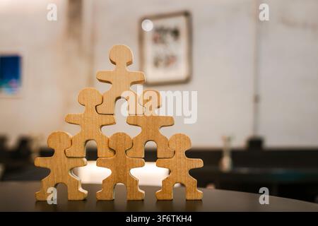 business teamwork structure concept with wooden people figures stacked in pyramid shape, representing organizational hierarchy, teamwork strength. Stock Photo