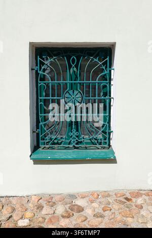 Aesthetic turquoise forged iron window bars cottagecore trend. Minimalist architectural lines on vintage white stucco wall facade with retro ornate Stock Photo