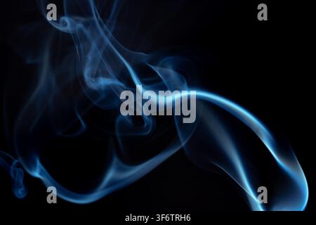 Wispy blue smoke wave flowing against a black background, creating a sense of mystery and elegance. Abstract and atmospheric concept. Concept of Stock Photo