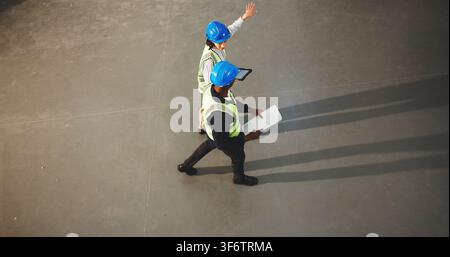 Architect, team and walking with tablet in warehouse for construction planning or instructions. Top view, people or civil engineer with documents or Stock Photo