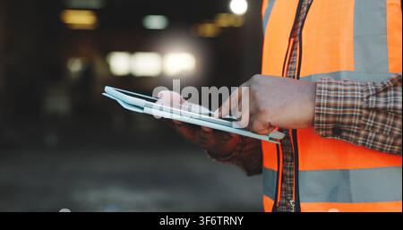 Construction, scroll or hands on site with tablet, task brief or inspection report on development. Space, man or engineer with tech, project Stock Photo