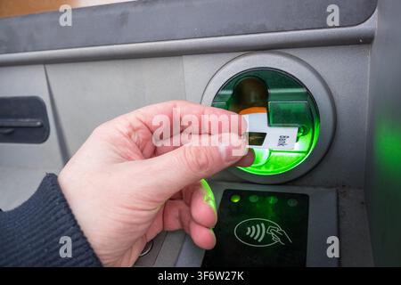 Lisboa, Janeiro 08, 2022: Hand inserting personalized bank card into atm machine for a financial transaction. Stock Photo