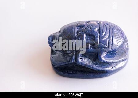 Carved blue lapis lazuli scarab beetle amulet isolated on white background. Stock Photo