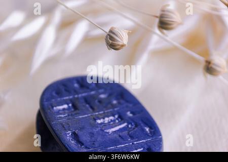 Macro shot of dried flax seed pods above blue stone amulet. Stock Photo