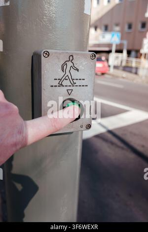 Hand pressing green pedestrian crossing button on a city street Stock Photo
