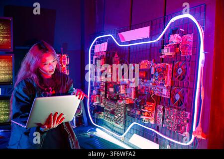 Software engineer typing coding in laptop computer at data center, Hacker woman is sitting at a desk with a laptop service in server room, Thinking an Stock Photo