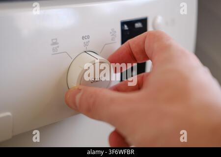 Hand selecting the eco cleaning program on a domestic dishwasher Stock Photo