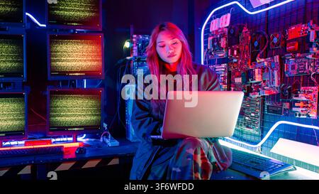 Asian woman is sitting at a desk with a laptop service in server room, Thinking and solve problems, Software engineer typing coding in laptop computer Stock Photo