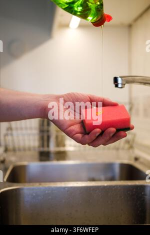 Hand preparing a pink sponge with dish soap for washing dishes Stock Photo