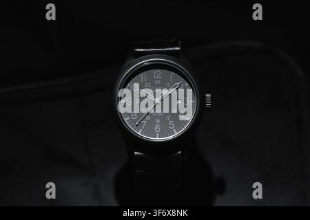 Shelton, USA - October 31, 2025: An all black tactical analog wristwatch with a date window is on black background. Timex Expediton all black, front v Stock Photo