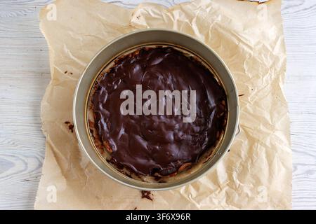 Overhead view of a freshly baked chocolate brownie in an unclasped opened springform pan lined with parchment paper. Stock Photo