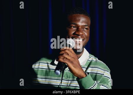 Smiling Black Student Holding Microphone Performing on Theater Stage Stock Photo