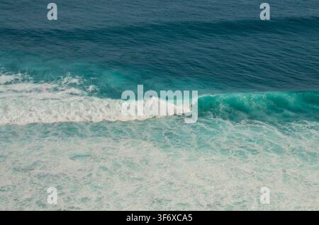 Powerful blue ocean wave crashing in the open sea during daytime, dramatic water splashes, close up view Stock Photo