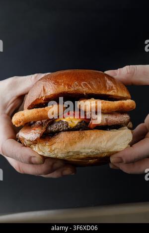 Small Inion Hand holding a fried onion ring above a small container of dipping ...