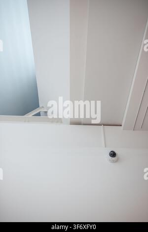 Security camera mounted on minimalist white ceiling architecture Stock Photo